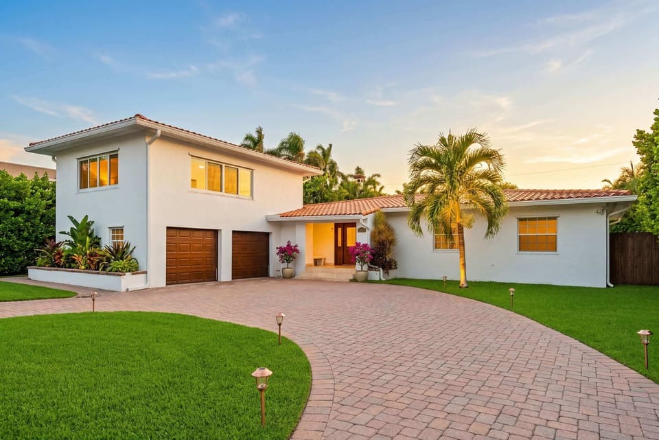  Bright white facade, lush greenery, and a spacious driveway await your arrival!