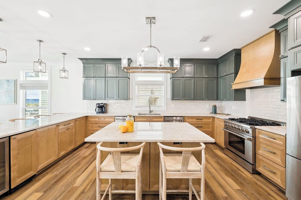 Your culinary haven awaits with a chef's kitchen featuring custom two-tone cabinetry, marble island, professional-grade appliances, and elegant pendant lighting—perfect for preparing memorable meals together.