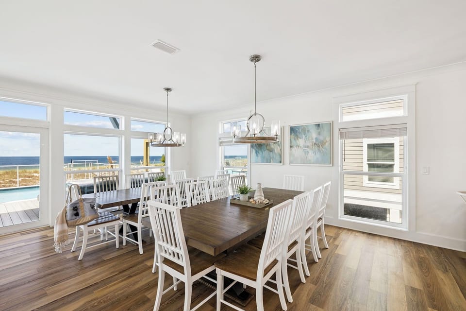 Gather everyone around this spacious dining table where sunlit meals meet stunning sea views through floor-to-ceiling windows, creating the perfect backdrop for your coastal escape.