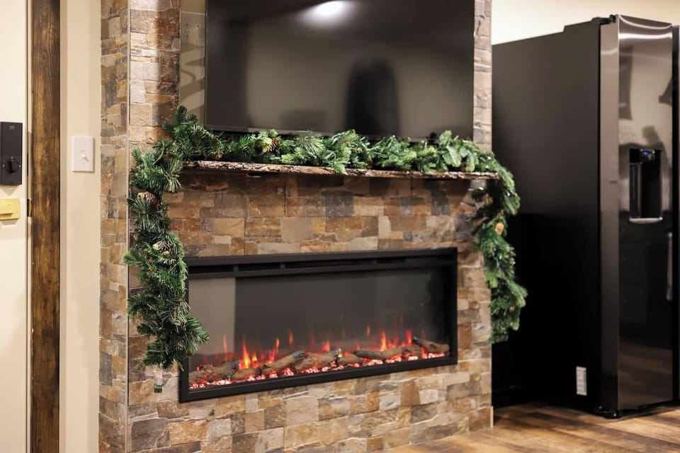 55” Roku Smart TV  - Streaming services accessible - Cable -Warm electric fireplace - Custom live edge wood fireplace mantel - Light up greenery