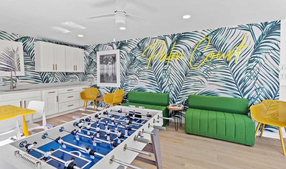 Shared lounge area features a foosball table, couches, chairs & tables.  