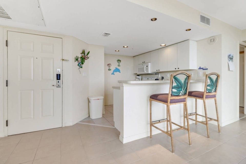 An eating bar with bar stools separates the open kitchen from the main living area.