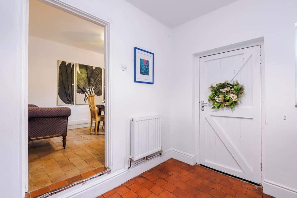 This cottage-style kitchen is modern and fully equipped, featuring bold blue cabinetry and tiled floors. It offers access to the backyard, creating a bright and functional space for cooking and entertaining.