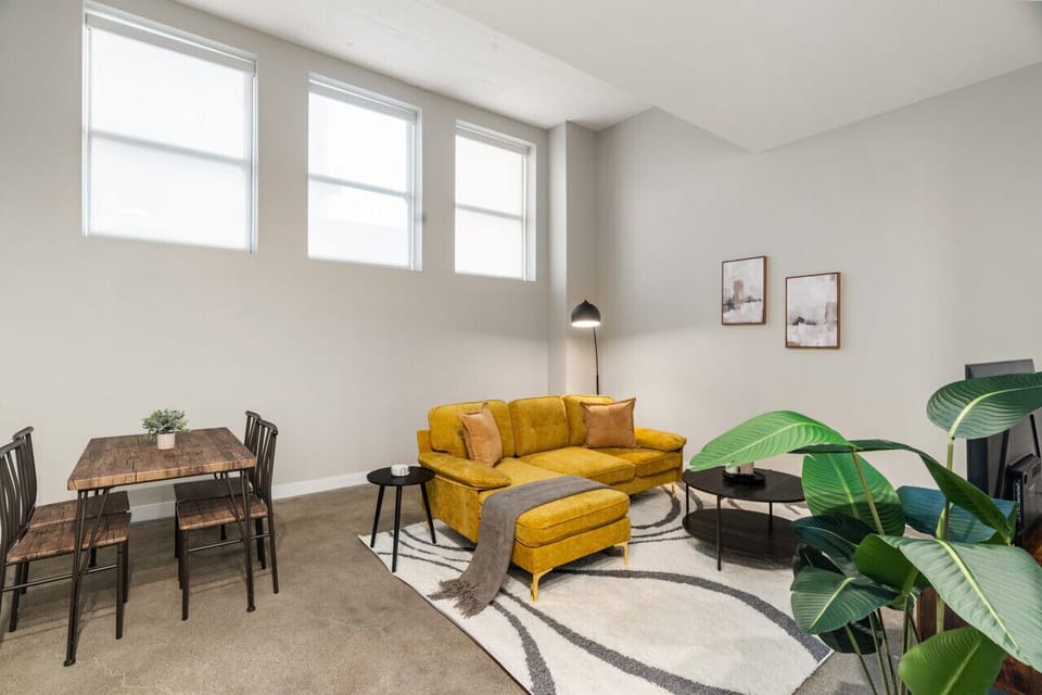 Spacious open-concept living and dining area featuring a vibrant sofa, modern furnishings, and a stylish entertainment setup—ideal for gatherings and relaxation.