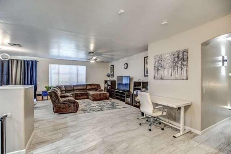 Bright and spacious living room with reclining sectional, smart TV and workspace.