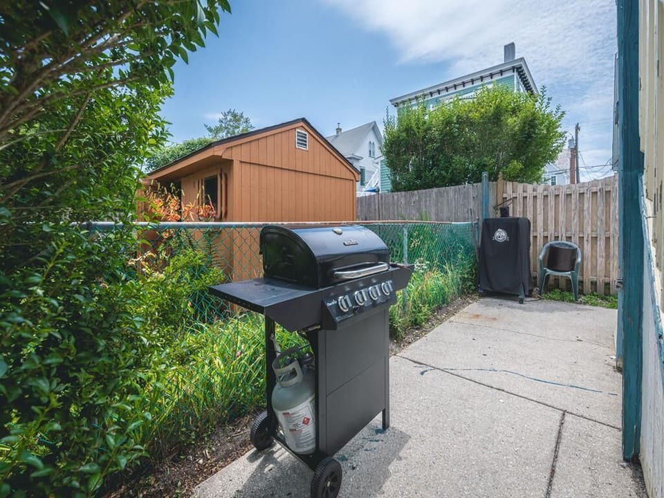 Ground-level BBQ area surrounded by greenery, perfect for grilling up your favorite meals during your stay.