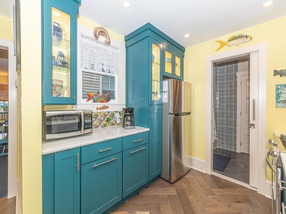 Additional kitchen view showcasing ample counter space, vibrant cabinetry, and a stainless steel refrigerator for your cooking convenience.