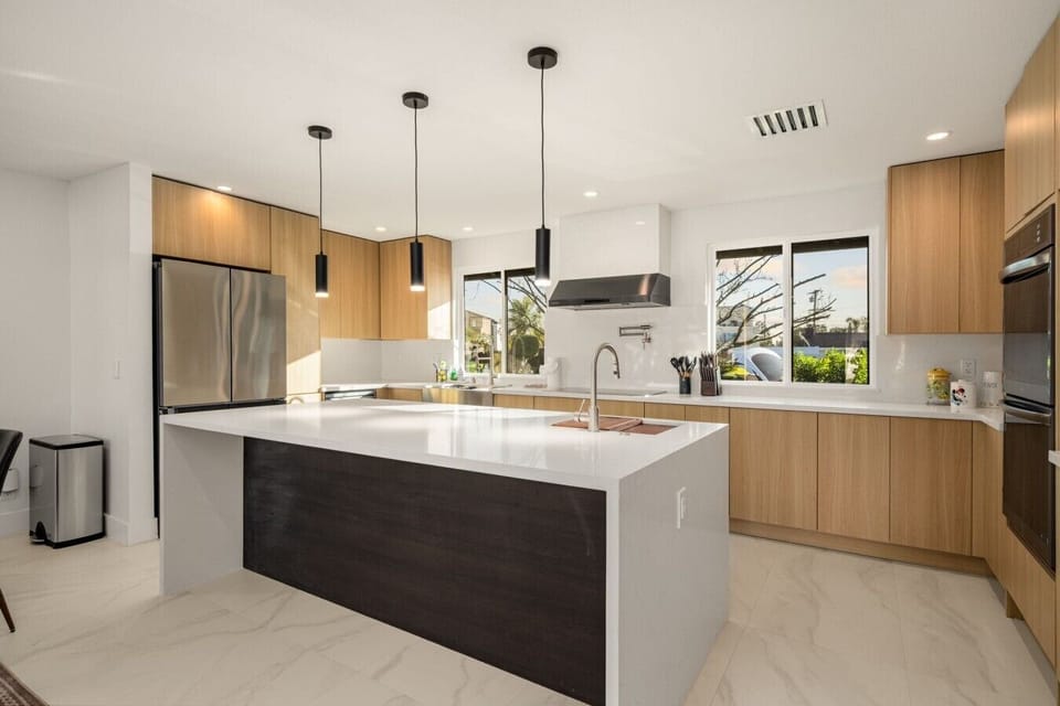 A striking waterfall island anchors the sleek, newly renovated kitchen, framed by warm wood cabinetry and modern pendant lighting. Bright, polished, and fully equipped, it`s built for effortless cooking and easy conversation.