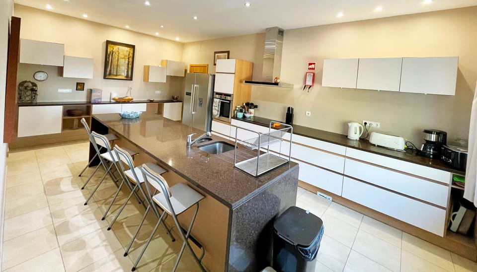 Modern kitchen at Villa Mandarin with breakfast bar, bar stools, and fully equipped cooking facilities, perfect for preparing meals during your Algarve holiday near Carvoeiro