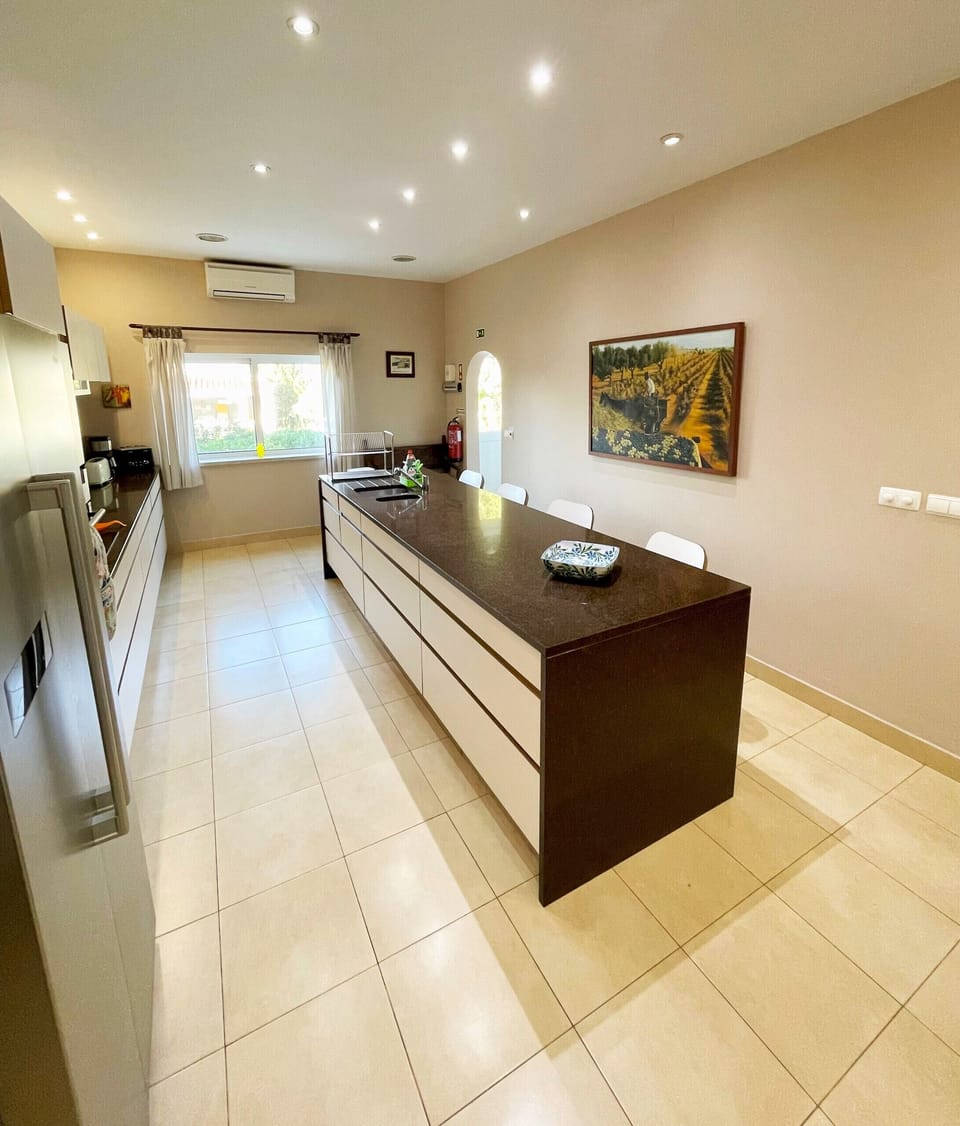 Fully equipped kitchen at Villa Mandarin with dark wood cabinets, modern appliances, tiled flooring, and air conditioning for self-catering holidays in the Algarve near Carvoeiro