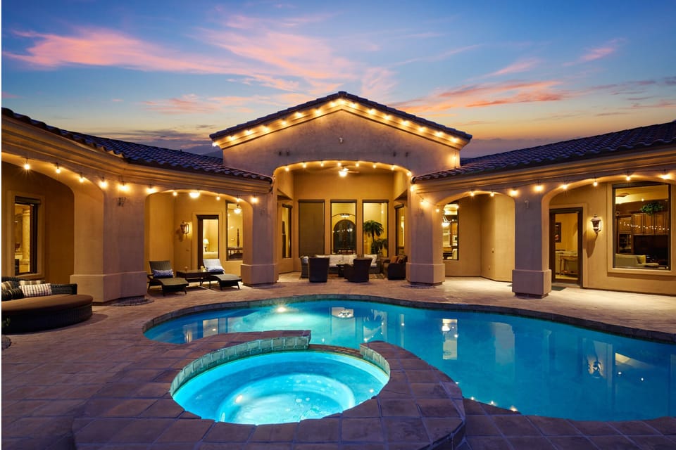 Outdoor oasis featuring a sparkling pool and hot tub. Multiple seating areas, lounge chairs, ping pong table, porch swing, outdoor grill with a built-in burner and mini-fridge, cornhole, putting green, and a gazebo.