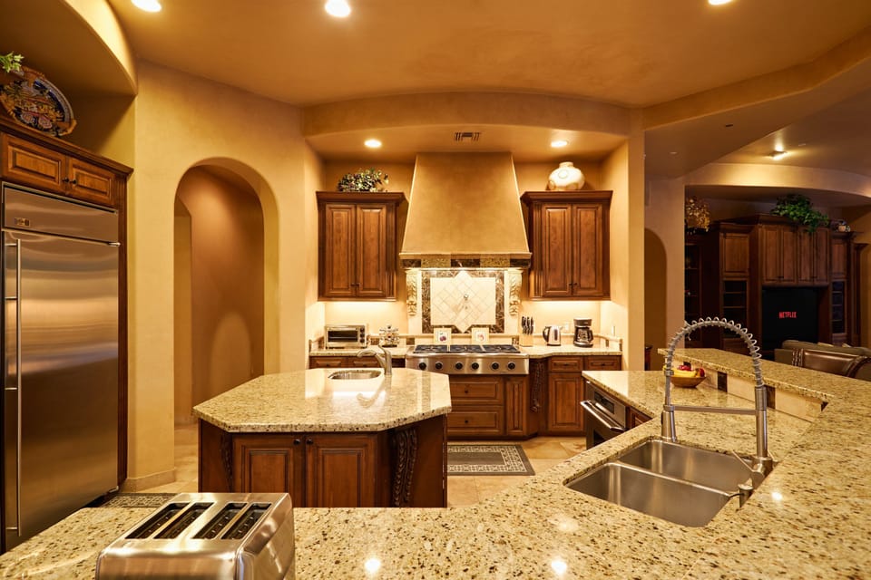 A stunning open-concept chef's kitchen, fully equipped with premium stainless-steel appliances, cooking essentials for your culinary creations, an informal dining table, and a sleek breakfast bar for casual seating.