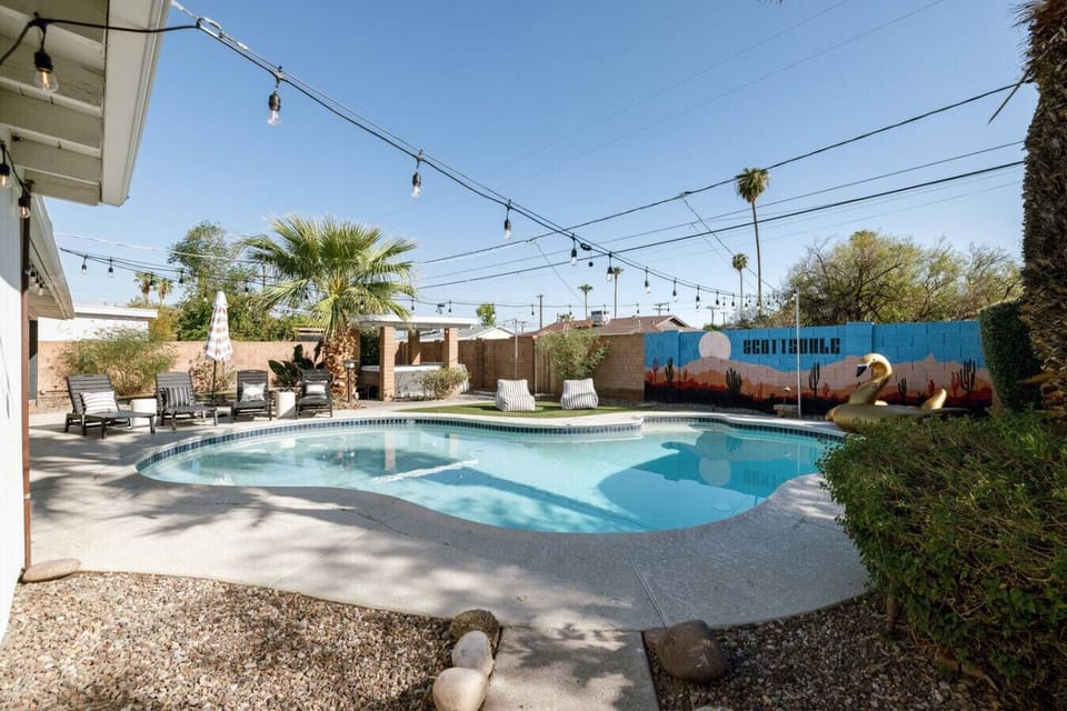 Resort-style backyard with *heated pool, hot tub, covered patio, outdoor grilling area, and a statement mural.