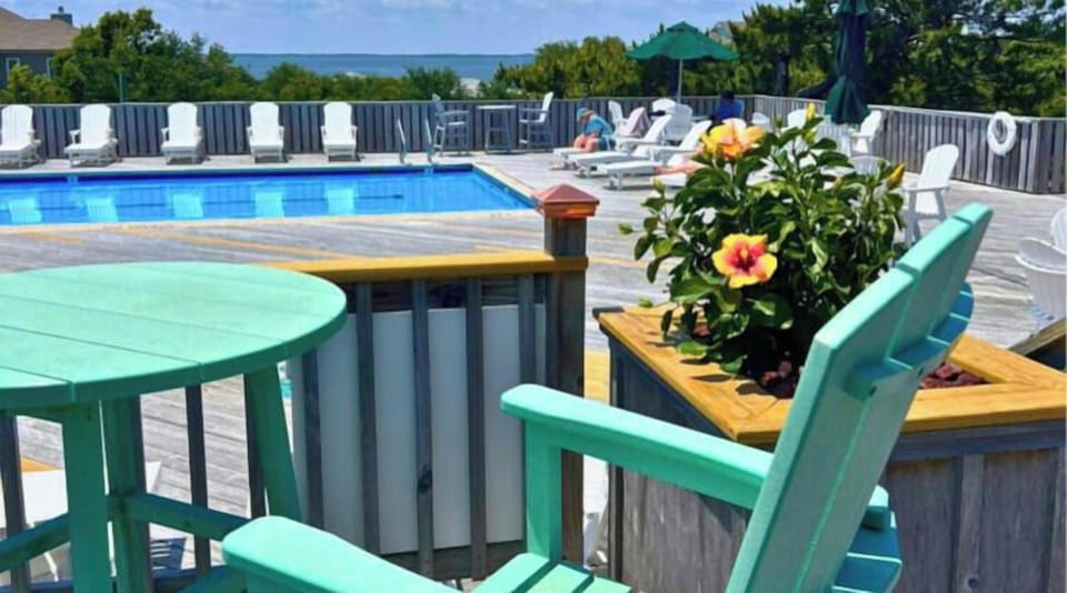 Relax by your sparkling community pool with ample lounge chairs, shaded seating, and vibrant floral touches overlooking serene water views.