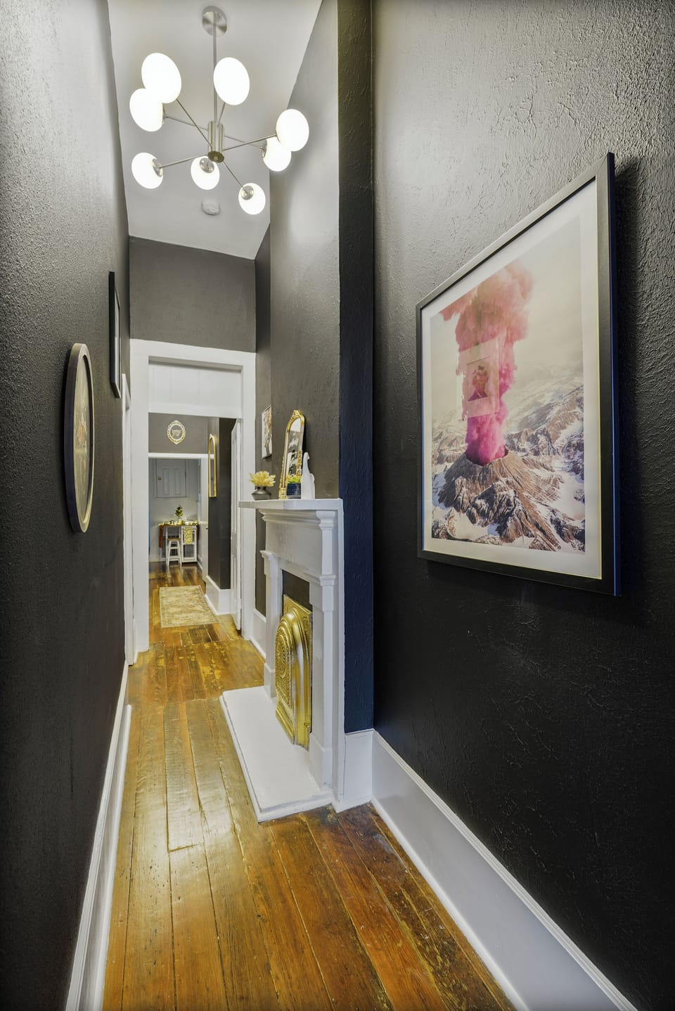 Stroll this epic hall: original wood floors, bold art, pink volcano & a stunning gold fireplace.