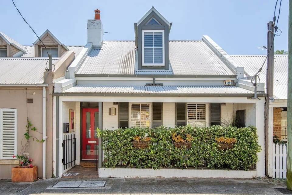 A classic Paddington terrace with a welcoming red door and leafy frontage.
