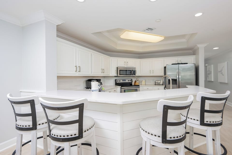 The kitchen features stainless appliances, white cabinets, and a spacious countertop perfect for meal prep and gatherings