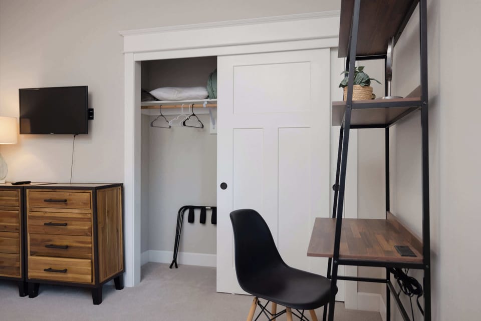 The first bedroom features a plush queen bed, desk, & smart TV