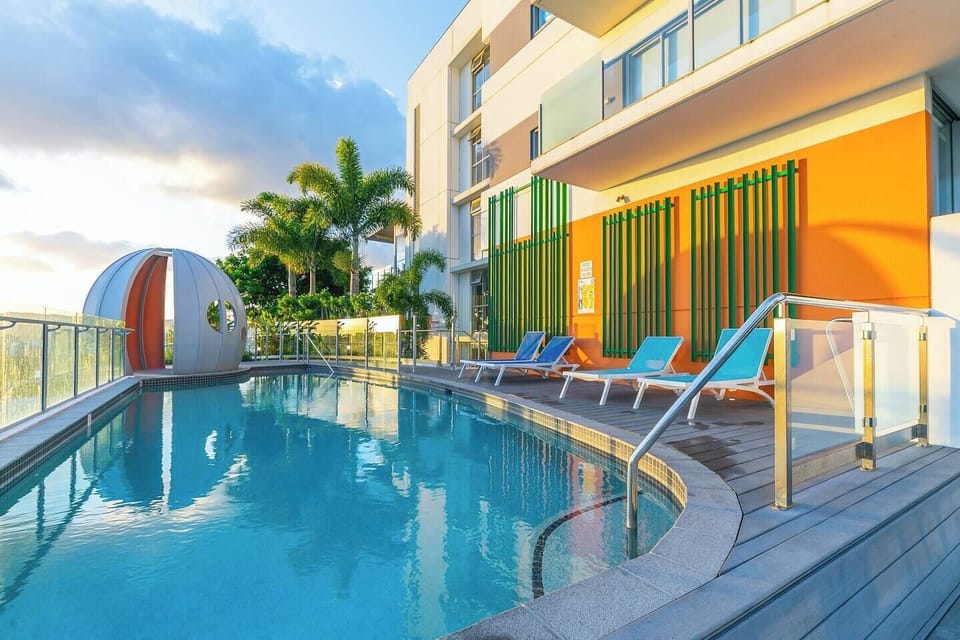 Take a refreshing dip in the shared rooftop pool surrounded by lush greenery and vibrant cityscapes.