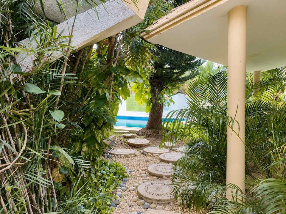 Lush garden path winding through tropical greenery toward the pool, a peaceful escape into nature