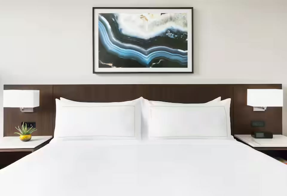 Sink into crisp linens beneath calming modern artwork.