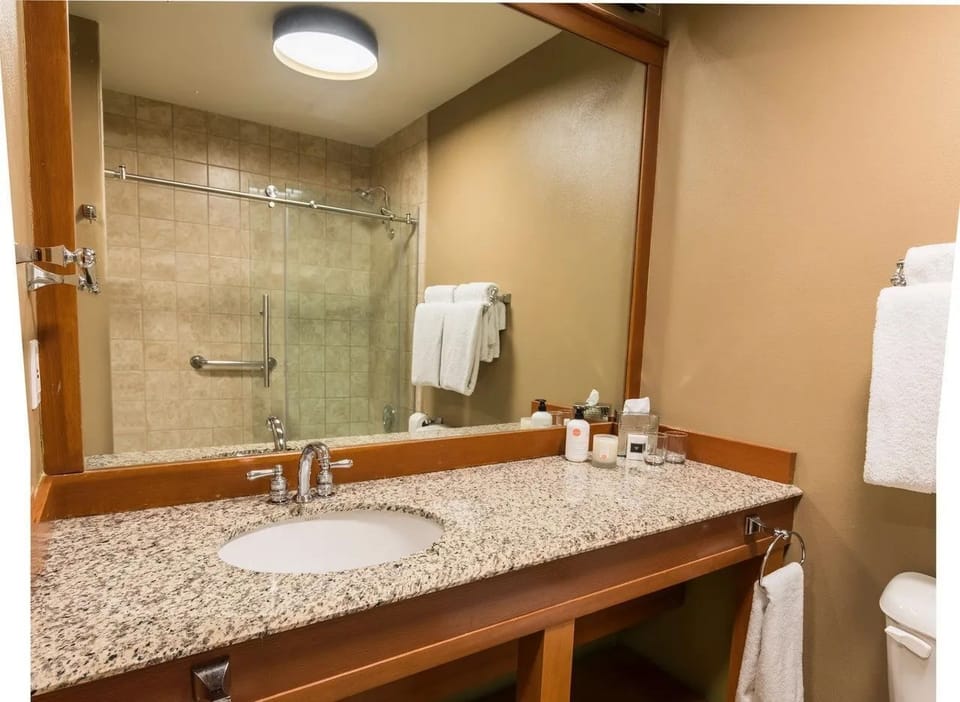 A warm, well-lit bathroom with a sleek walk-in shower and spacious vanity, offering a calm space to refresh and unwind.