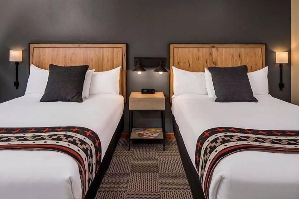 A cozy and stylish room with plush twin beds and soft lighting, designed for a peaceful night’s rest.