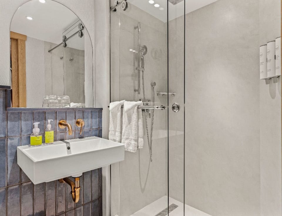 A sleek bathroom with a walk-in shower and elegant fixtures, providing a refreshing and calming space to unwind.