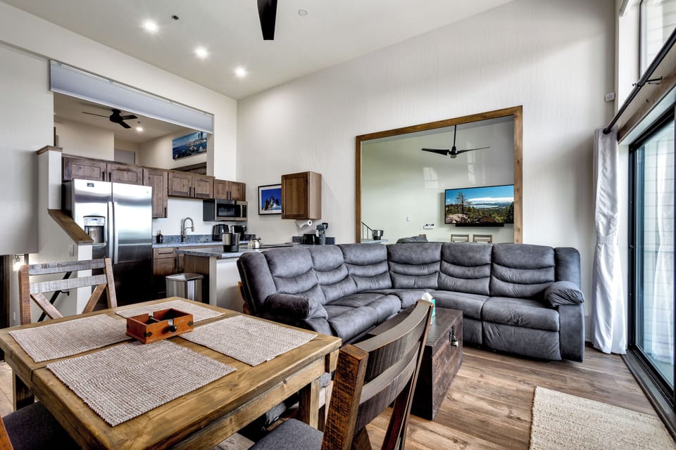 Spacious open-concept living area with a plush sectional sofa, rustic dining table, and a fully equipped kitchen.