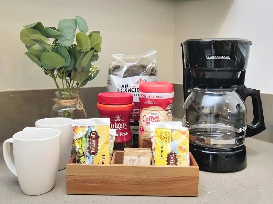 Well-stocked coffee station with a coffee maker, mugs, and a variety of coffee and tea options.