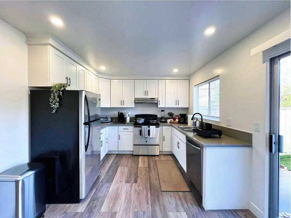 Bright and airy kitchen with white cabinets, stainless steel appliances, and a view of the backyard.