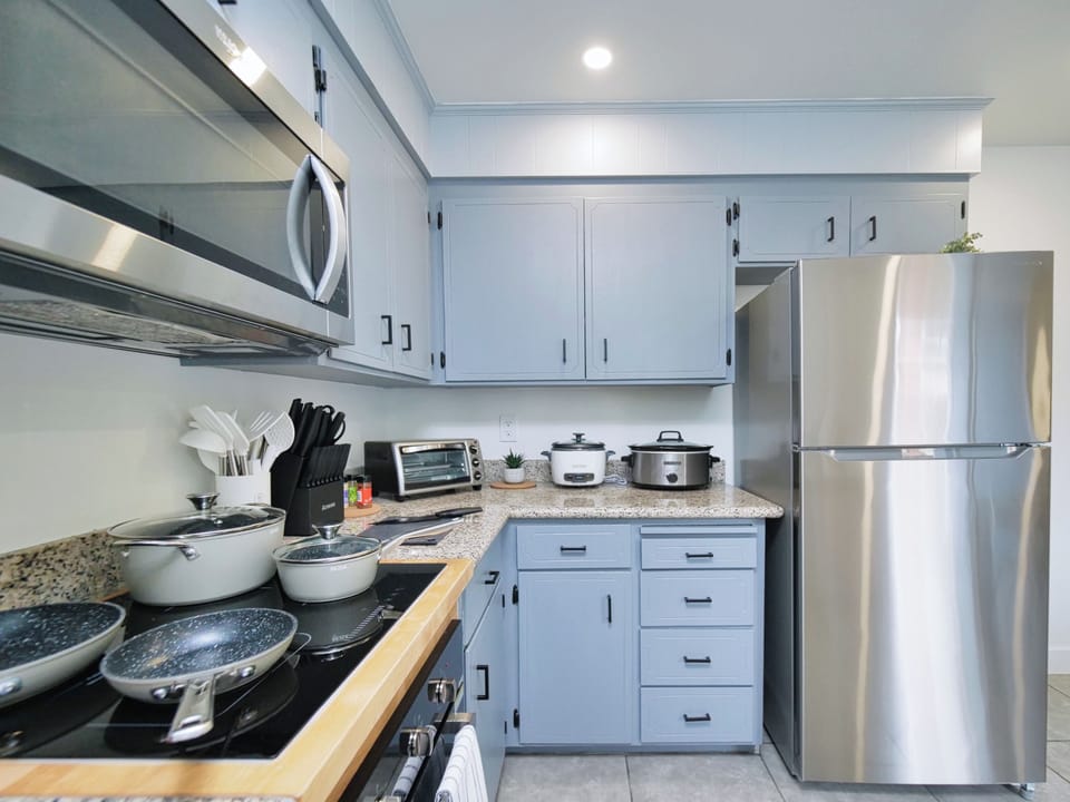 kitchen with a microwave, toaster oven, fridge, slow cooker, and a full set of pots and pans.