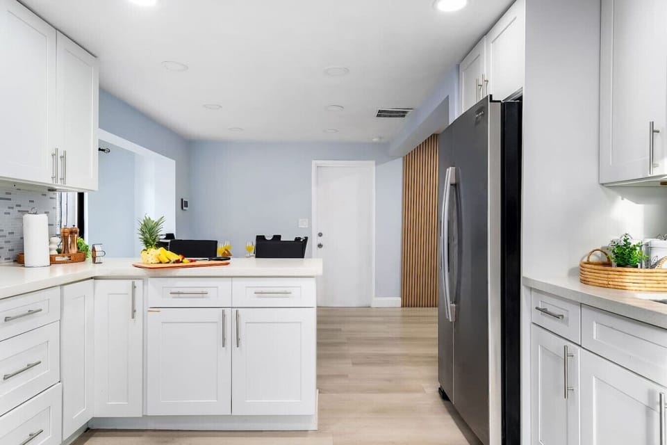 Modern fully equipped kitchen with stainless steel appliances, oven, microwave, toaster, blender, coffee maker, cookware, dishes, utensils, spacious countertops, and ample storage.