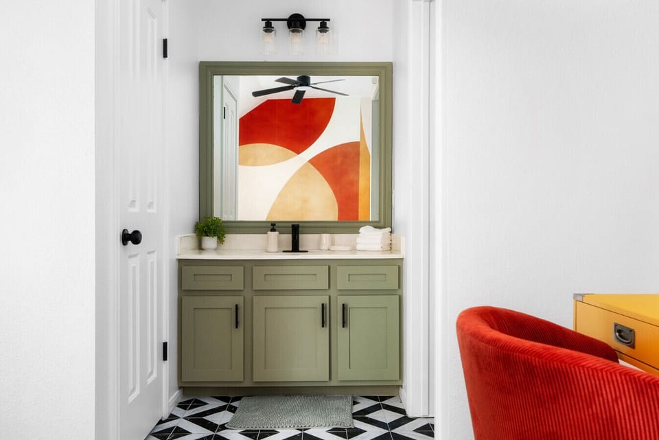 Step into this stylish vanity space, featuring modern green cabinetry, bold artistic accents, and a sleek design for a refreshing start to your day!