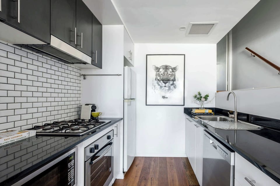 Fully equipped kitchen featuring a sink, refrigerator, microwave, oven, and stove – everything you need for convenient meal preparation.