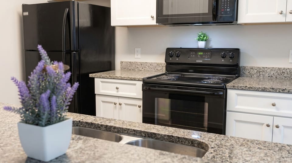Fully equipped kitchen with full-size refrigerator, electric stove, microwave, and granite countertops. Furnished apartment for rent in Columbus, GA — ideal for extended stays, military relocation, and traveling professionals near Fort Benning.