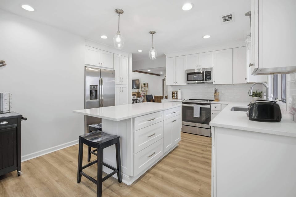 Modern kitchen with white cabinetry, stainless steel appliances, and a central island for casual dining.
