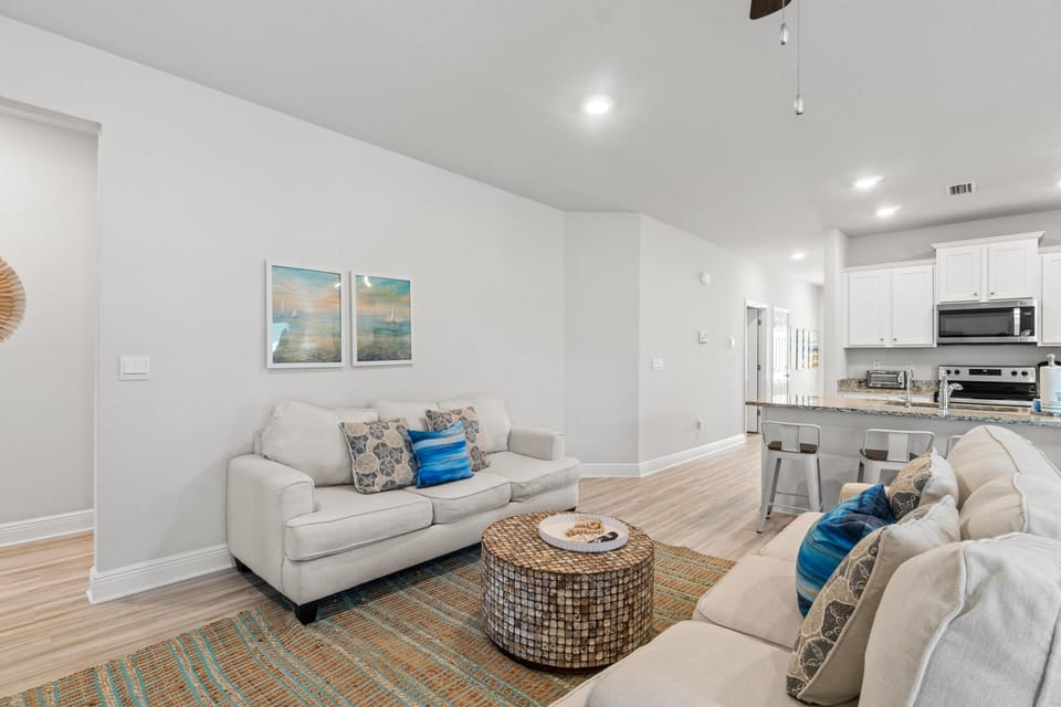Unwind in your bright living space with cozy seating and ocean-inspired touches, flowing seamlessly into the modern kitchen.