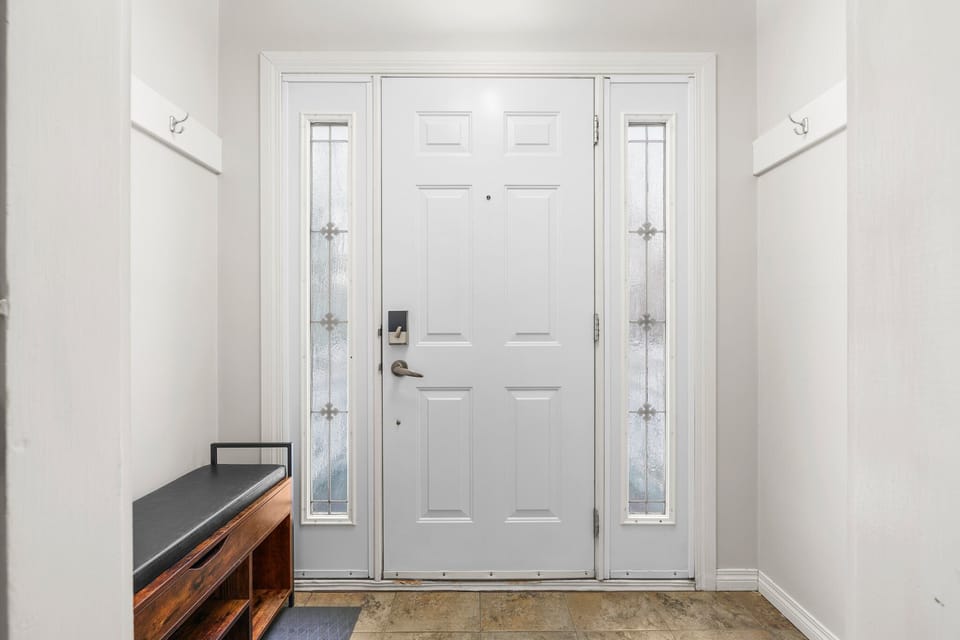 Welcoming entryway with a bright front door, bench seating.