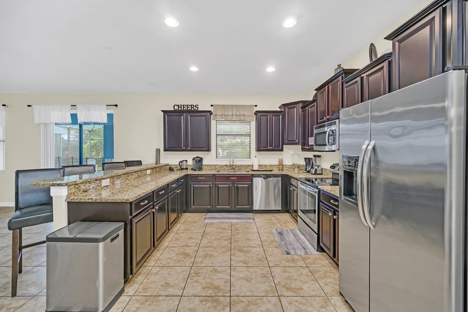 The fully equipped open-concept kitchen features stainless steel appliances, ample counter space, and everything you need to prepare and enjoy family meals during your vacation.