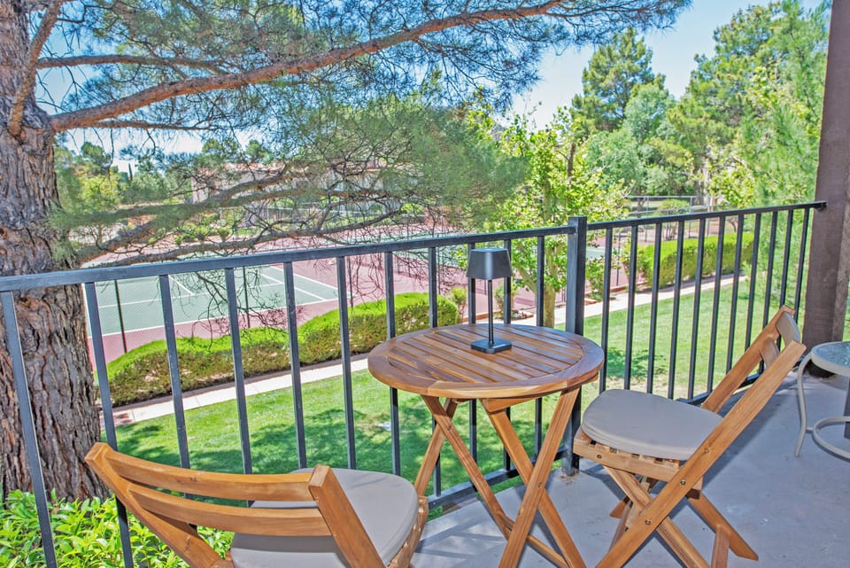 Private shaded balcony with seating for four overlooking a park-like setting