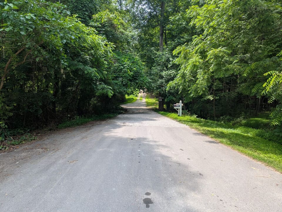 The roadway to the property includes a small concrete bridge over the creek at the end of the neighborhood, followed by gravel and dirt roads leading to the home.
