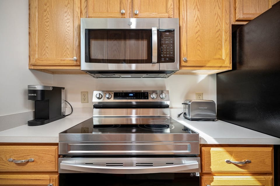 Sleek stainless steel range & microwave framed by rich wood cabinetry