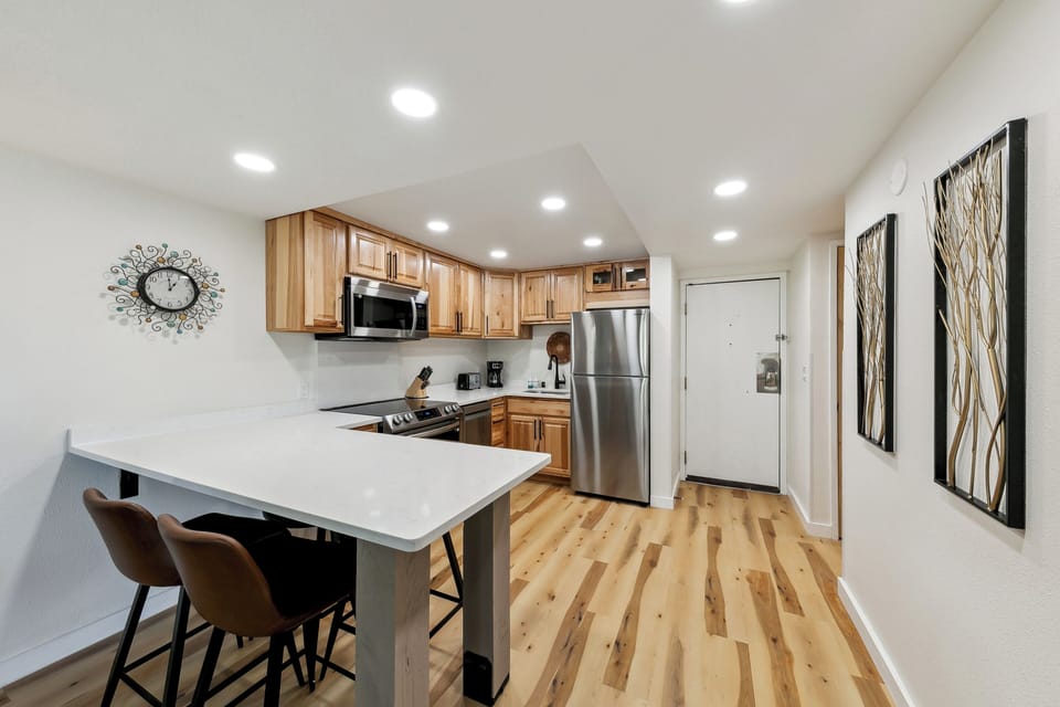 Your fully equipped kitchen features warm wood cabinets, stainless appliances, and a breakfast bar where you can enjoy morning coffee.