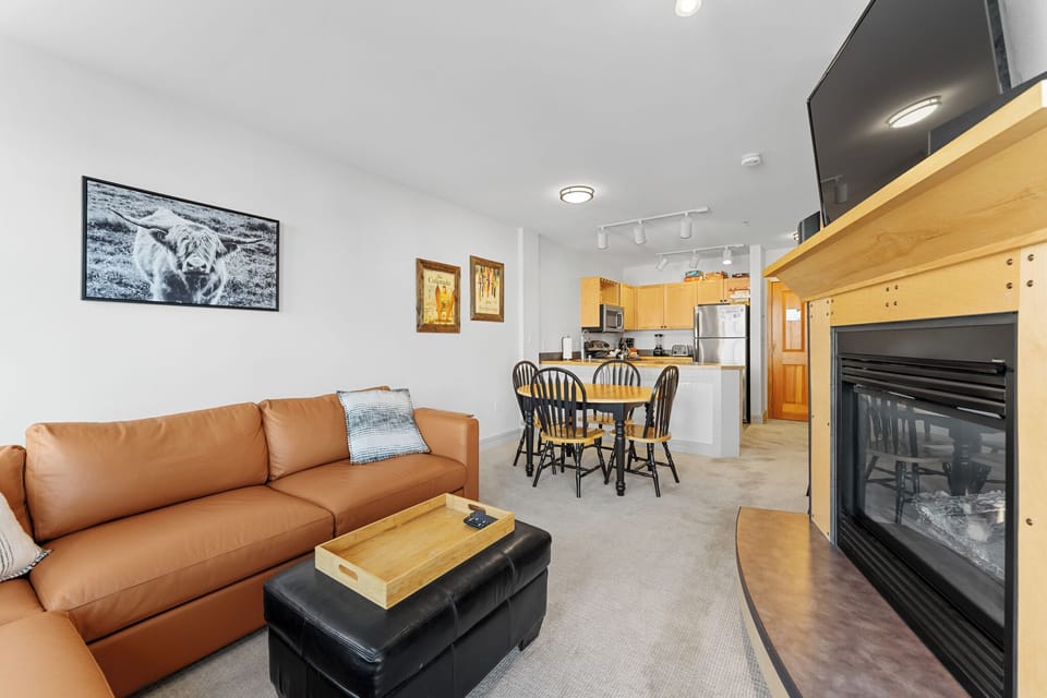 Living area featuring a mounted TV over a gas fireplace, queen sleeper sofa, and balcony access.