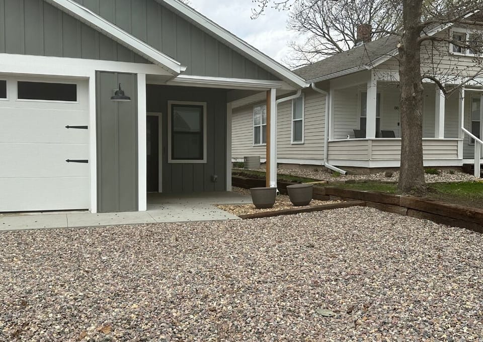 Both houses next to one another. The new build is the gray. The house with the white porch is the older home.