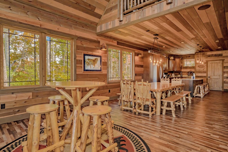 Warm rustic cabin kitchen with log furniture, large tables, and cozy light.
