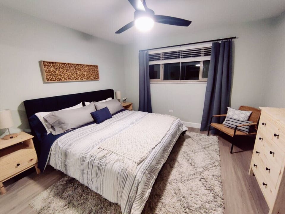 A cozy bed, stylish dresser, and a sunlit window create the perfect ambiance for relaxation