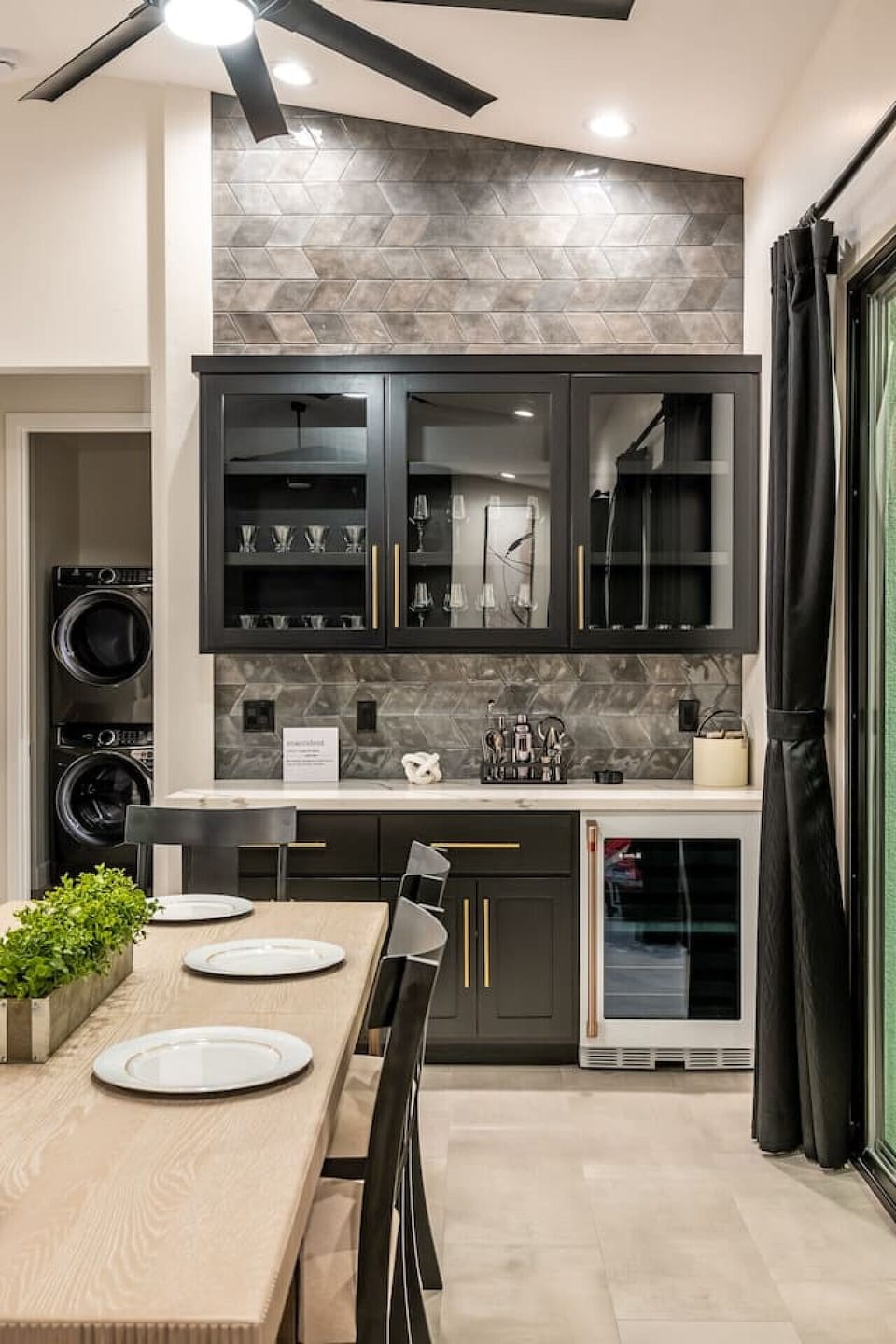 Elegant dining area with a view of the stylish kitchen- A chic bar area with glass cabinets, wine fridge, and modern backsplash adds sophistication, perfect for entertaining or enjoying a quiet meal