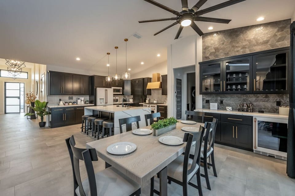 Elegant dining area with a view of the stylish kitchen- A chic bar area with glass cabinets, wine fridge, and modern backsplash adds sophistication, perfect for entertaining or enjoying a quiet meal